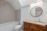 This modern bathroom features a sleek bathtub with a tiled accent wall and a convenient showerhead.