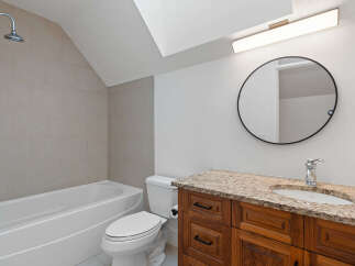 This modern bathroom features a sleek bathtub with a tiled accent wall and a convenient showerhead.