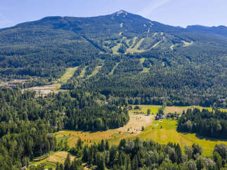 Experience the ultimate mountain lifestyle with this stunning aerial view of a property nestled amidst lush forests and rolling hills.