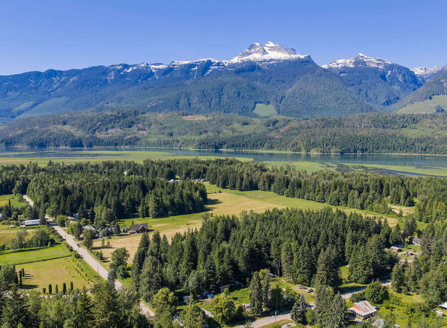 Discover serene living in this picturesque landscape, featuring a tranquil lake and majestic snow-capped mountains as your backdrop.