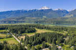 Discover serene living in this picturesque landscape, featuring a tranquil lake and majestic snow-capped mountains as your backdrop.