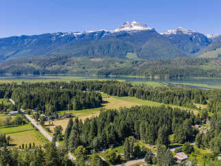 Discover serene living in this picturesque landscape, featuring a tranquil lake and majestic snow-capped mountains as your backdrop.