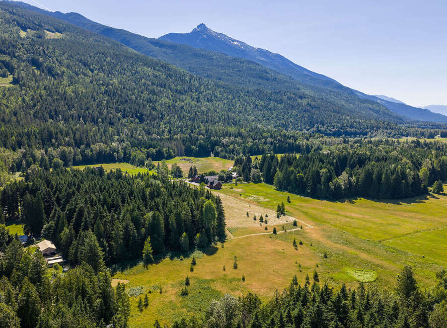 Discover this stunning rural property nestled amidst lush evergreen forests and rolling meadows, offering breathtaking mountain views.