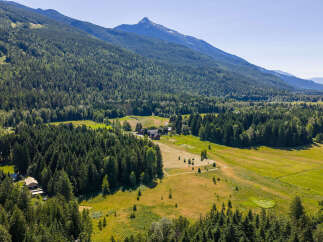 Discover this stunning rural property nestled amidst lush evergreen forests and rolling meadows, offering breathtaking mountain views.