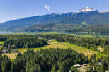 Discover this stunning property nestled amidst lush evergreen forests and rolling green fields, offering breathtaking views of a serene lake and majestic snow-capped mountains.