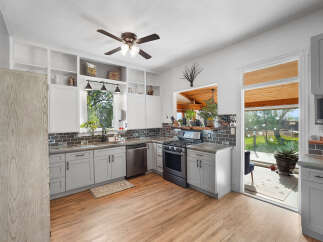 This charming kitchen boasts a sleek gray cabinetry complemented by a dark subway tile backsplash and a spacious window offering picturesque views.