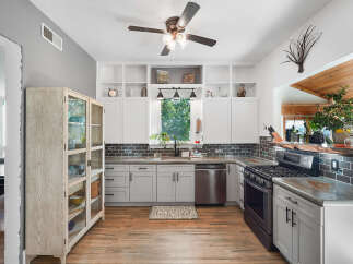Discover this beautifully updated kitchen featuring sleek white cabinetry, a modern subway tile backsplash, and durable concrete countertops.