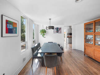 This dining room features a sleek, dark wood dining table paired with comfortable upholstered chairs and a bench, creating a modern and inviting space.