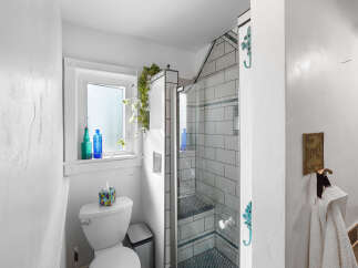 This charming bathroom features a modern tiled shower with a built-in bench, complemented by a sleek toilet and a decorative tissue box.
