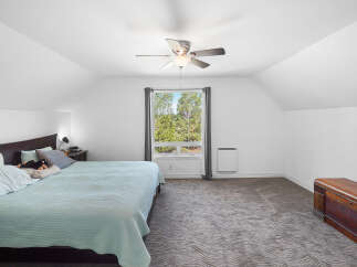 Experience comfort and style in this spacious bedroom, featuring a large bed with a plush teal comforter and a dark wood headboard.