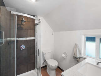 This bathroom features a modern shower with dark tiled walls and a sleek glass enclosure.