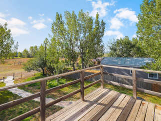 Enjoy the outdoors from this charming wooden deck, offering a peaceful vantage point of the surrounding natural landscape.