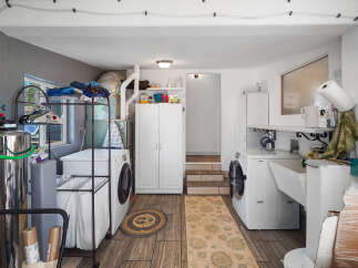 This laundry room boasts two washing machines, a utility sink, and ample storage with two tall white cabinets.