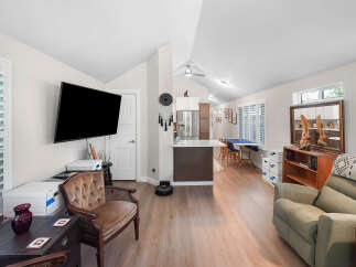 This spacious open-concept living area features a modern kitchen with stainless steel appliances and a breakfast bar, seamlessly flowing into a comfortable living room.