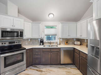 This spacious kitchen features sleek stainless steel appliances, including a microwave, oven, and dishwasher, complemented by a modern refrigerator.