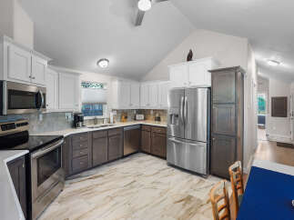 Experience modern living in this stunning kitchen featuring sleek stainless steel appliances, including a French door refrigerator and a built-in microwave.