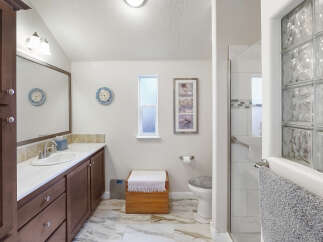 This bright and airy bathroom features a spacious vanity with ample storage, a clean white sink, and a large mirror.