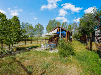 Enjoy outdoor living in this charming property featuring a cozy cabin-style home with a welcoming deck and patio area.