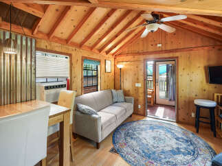 Step into this charming cabin featuring a cozy living area with a comfortable sofa and a rustic dining space.