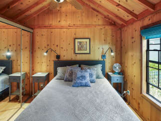 Experience cozy comfort in this charming bedroom featuring a plush bed adorned with decorative pillows and a textured quilt.