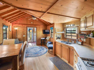 Experience cozy living in this charming cabin featuring a fully equipped kitchen with ample cabinet space and a double sink.