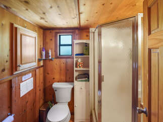 This charming bathroom features warm wood paneling throughout, creating a cozy and rustic atmosphere.