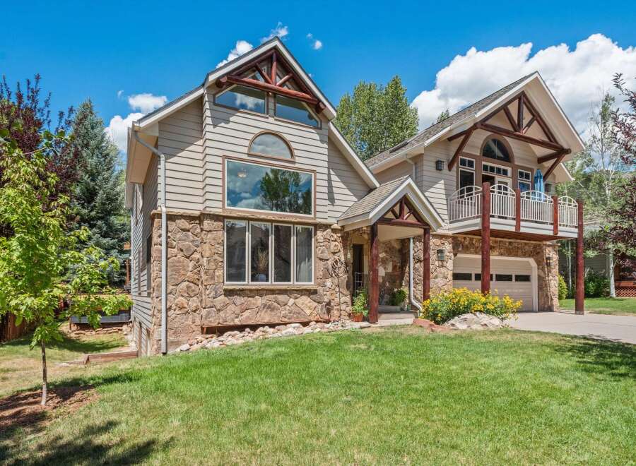 Experience mountain living in this stunning home featuring a unique stone and siding exterior, complemented by rustic log accents and a charming covered porch.