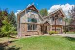 Experience mountain living in this stunning home featuring a unique stone and siding exterior, complemented by rustic log accents and a charming covered porch.