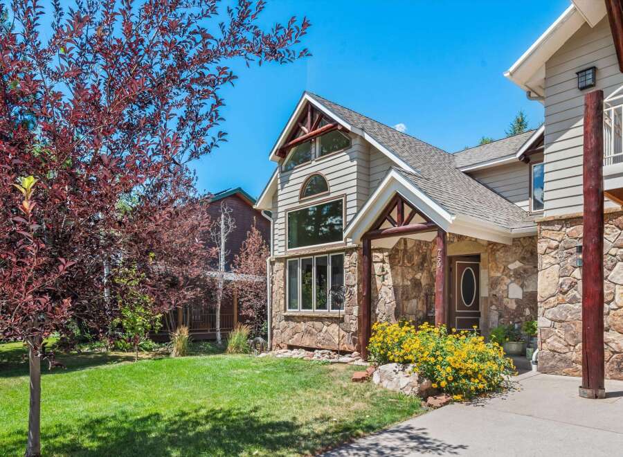 Experience mountain living in this charming home featuring a striking stone facade and rustic wooden accents.