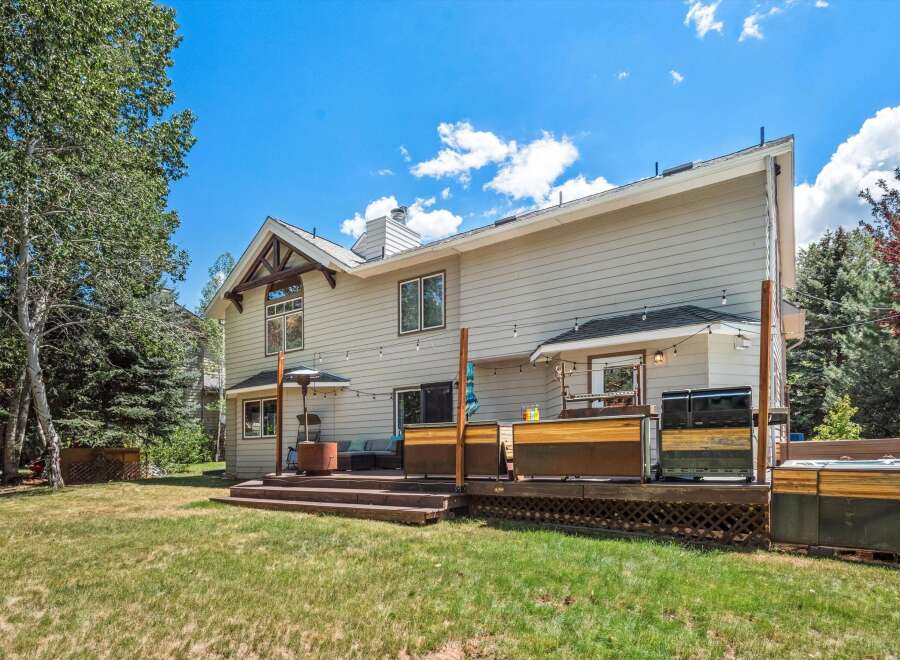 Enjoy outdoor living with this spacious deck featuring a hot tub, grill, and ample seating areas perfect for entertaining.