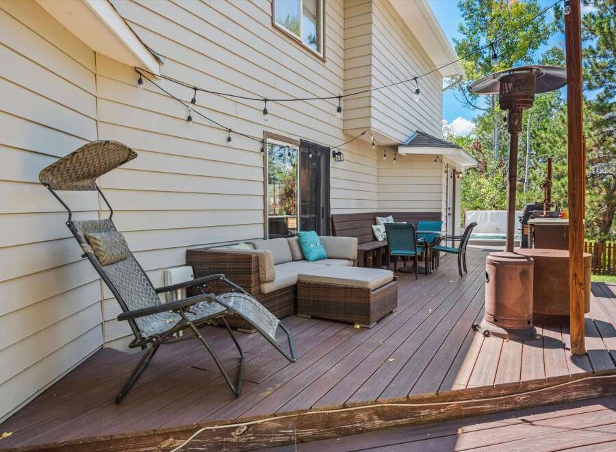 Enjoy outdoor living on this spacious deck featuring a comfortable sectional sofa, dining set, and a relaxing lounge chair.