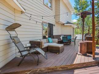 Enjoy outdoor living on this spacious deck featuring a comfortable sectional sofa, dining set, and a relaxing lounge chair.