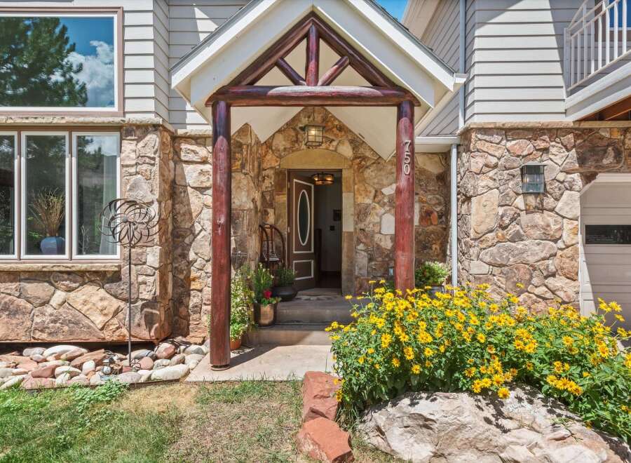 Discover this charming home featuring a rustic stone facade and a welcoming covered entryway with log accents.