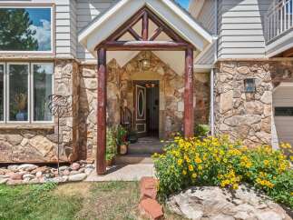 Discover this charming home featuring a rustic stone facade and a welcoming covered entryway with log accents.