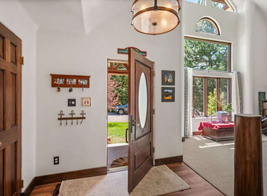 Step into a grand entryway featuring a beautiful wooden door with an oval glass insert, welcoming you into a home filled with natural light.