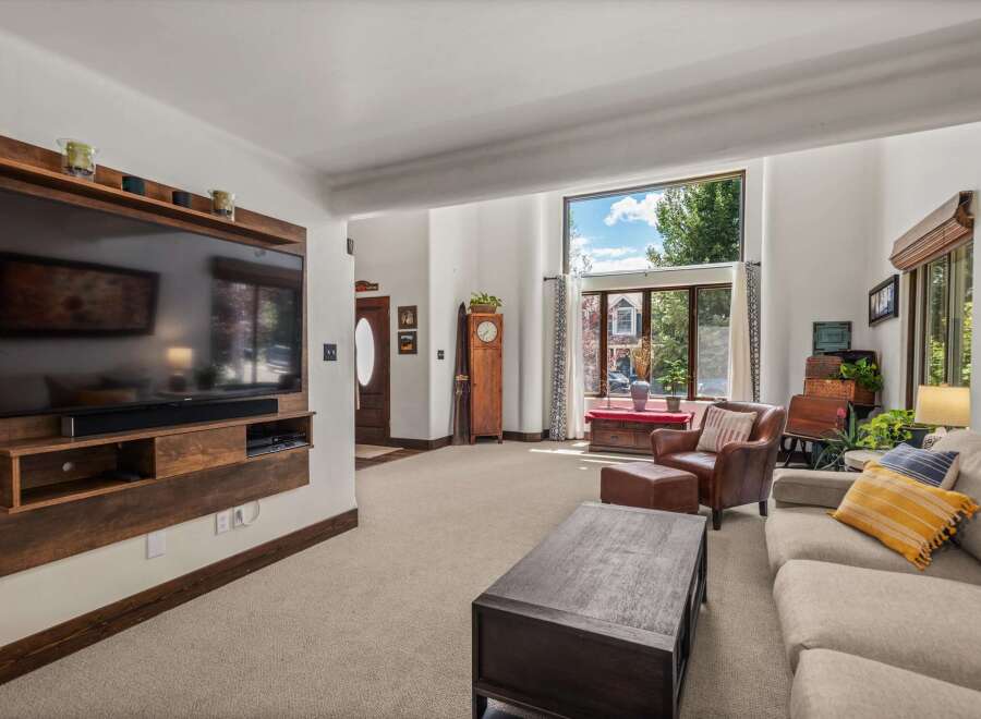 This spacious living room features a large wall-mounted TV with a custom wood surround, perfect for entertainment.