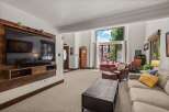 This spacious living room features a large wall-mounted TV with a custom wood surround, perfect for entertainment.
