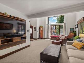 This spacious living room features a large wall-mounted TV with a custom wood surround, perfect for entertainment.