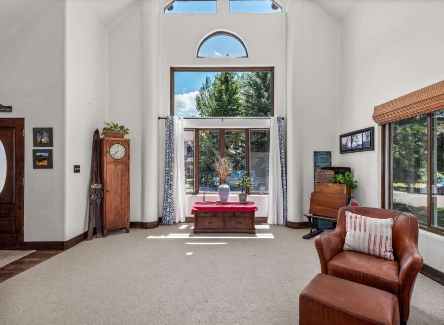 Step into this grand living room featuring soaring vaulted ceilings and a magnificent wall of windows that floods the space with natural light.