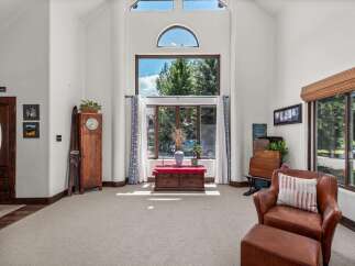 Step into this grand living room featuring soaring vaulted ceilings and a magnificent wall of windows that floods the space with natural light.