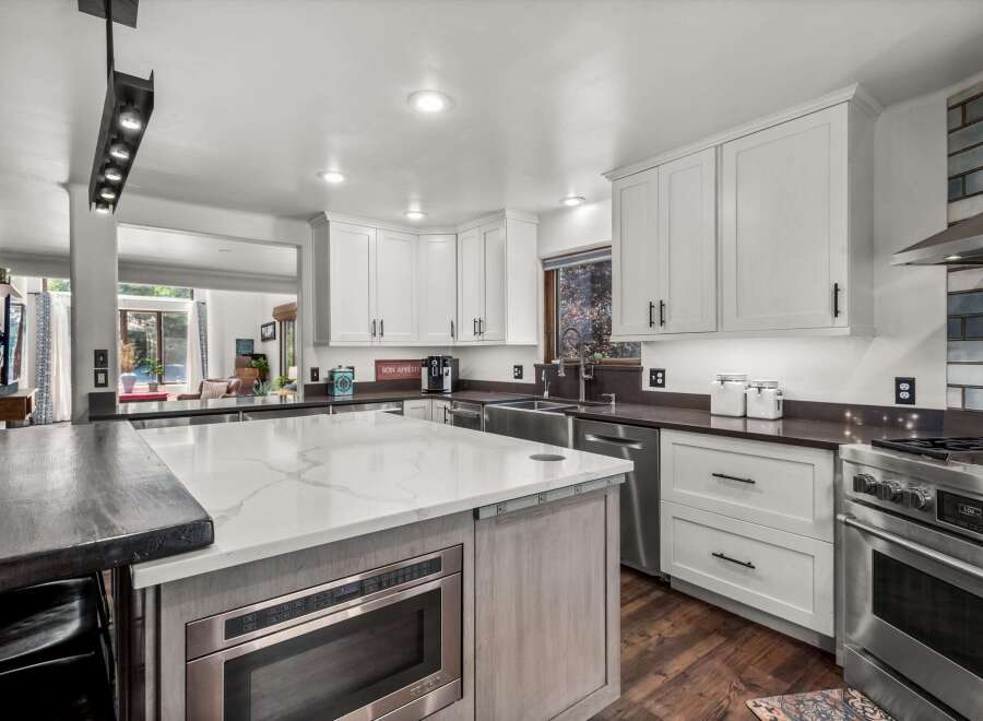 Experience culinary excellence in this stunning modern kitchen, featuring sleek white cabinetry, a spacious quartz island with a built-in microwave, and high-end stainless steel appliances.