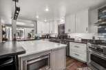 Experience culinary excellence in this stunning modern kitchen, featuring sleek white cabinetry, a spacious quartz island with a built-in microwave, and high-end stainless steel appliances.