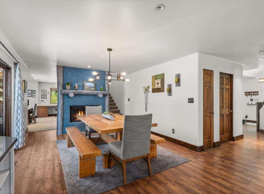 Experience cozy living in this inviting dining area, featuring a rustic wooden table and benches set against a striking blue accent wall with a fireplace.