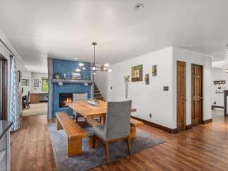 Experience cozy living in this inviting dining area, featuring a rustic wooden table and benches set against a striking blue accent wall with a fireplace.