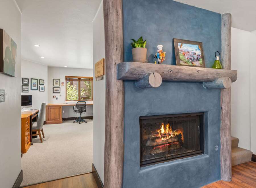 Cozy up by the rustic stone fireplace, featuring a natural wood mantel adorned with charming decor.