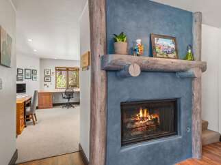 Cozy up by the rustic stone fireplace, featuring a natural wood mantel adorned with charming decor.