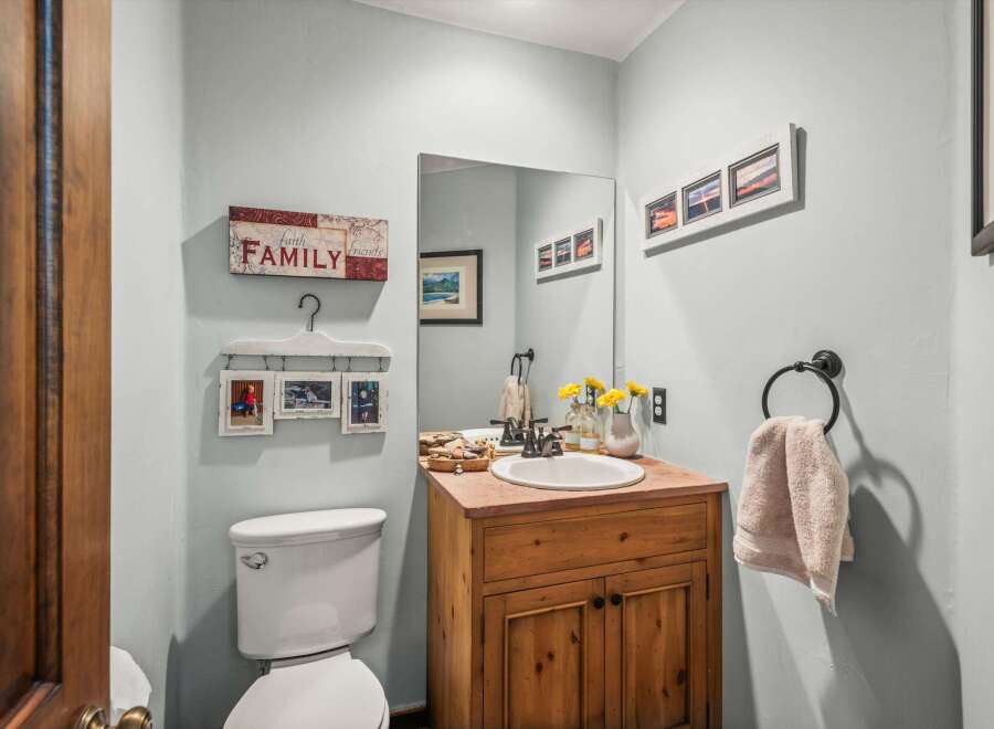 This charming bathroom features a rustic wooden vanity with a stone countertop, complementing the light blue walls.