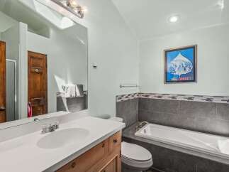 This bathroom features a spacious vanity with a white countertop and wooden cabinetry, complemented by a large mirror.