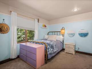 This charming bedroom features a cozy queen-size bed with a plush blue throw, perfect for relaxing evenings.