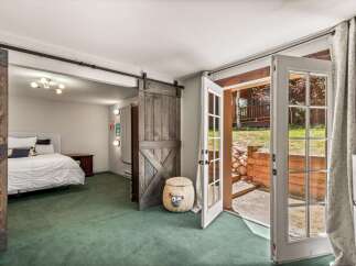 Step into this charming bedroom featuring a cozy queen-size bed and a unique barn door for a rustic touch.